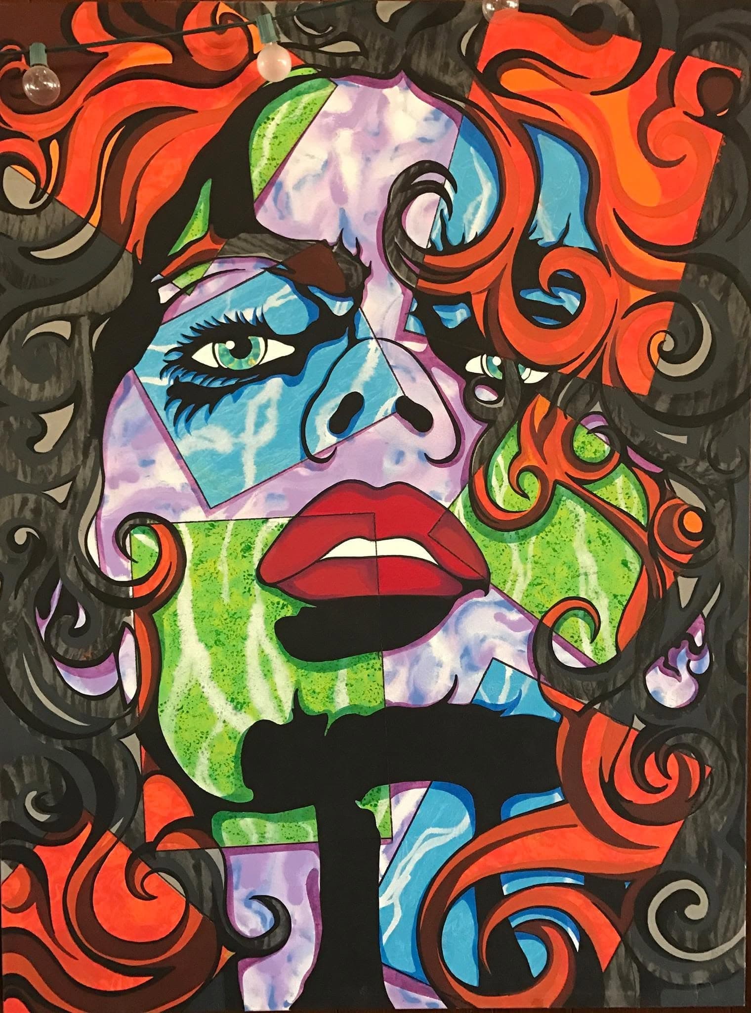 A face broken into faceted planes of blue, green and lilac, framed by swirling orange and black hair.